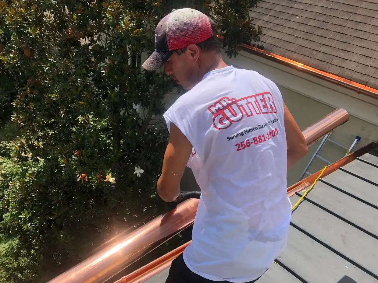 Construction worker holding a copper gutter section during installation preparation in Madison, AL